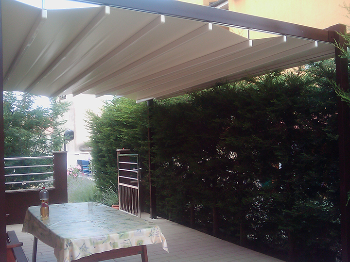 wooden pergola with cream awning stretched over small outdoor seating section